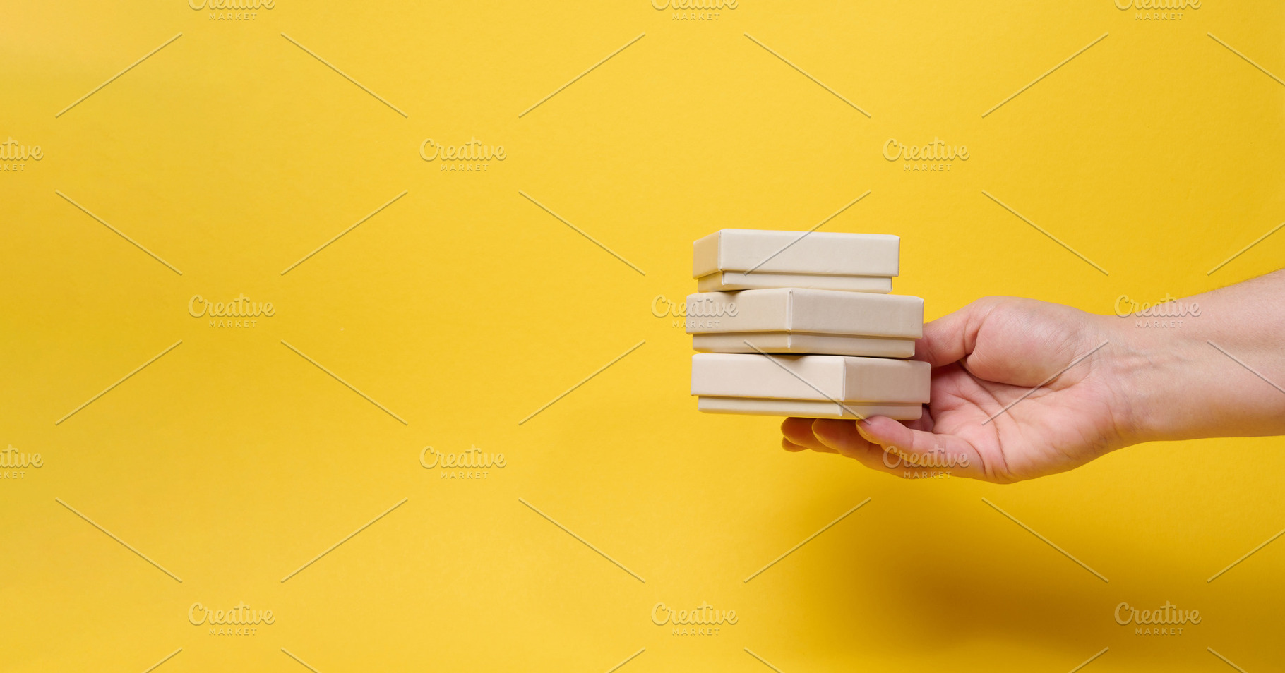 A woman's hand holds a stack of three small gift boxes on a brig, a Holiday Photo by ndanko