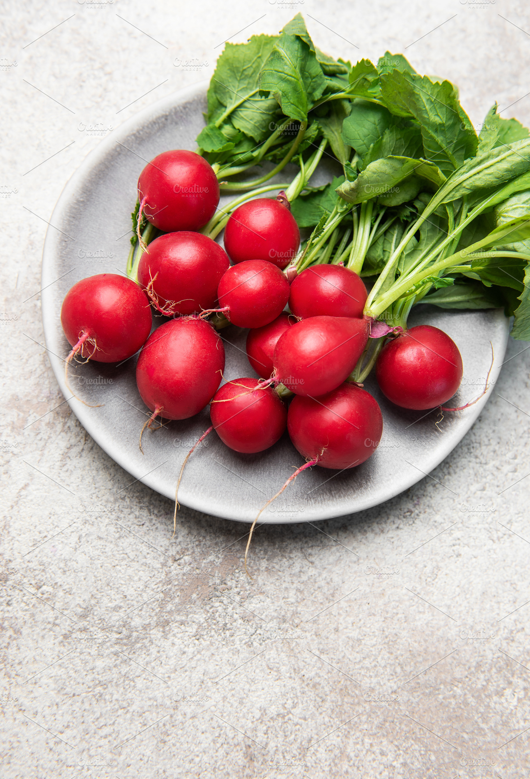 Fresh red radishes with green leaves on plate, a Food & Drink Photo by Olena Rudo