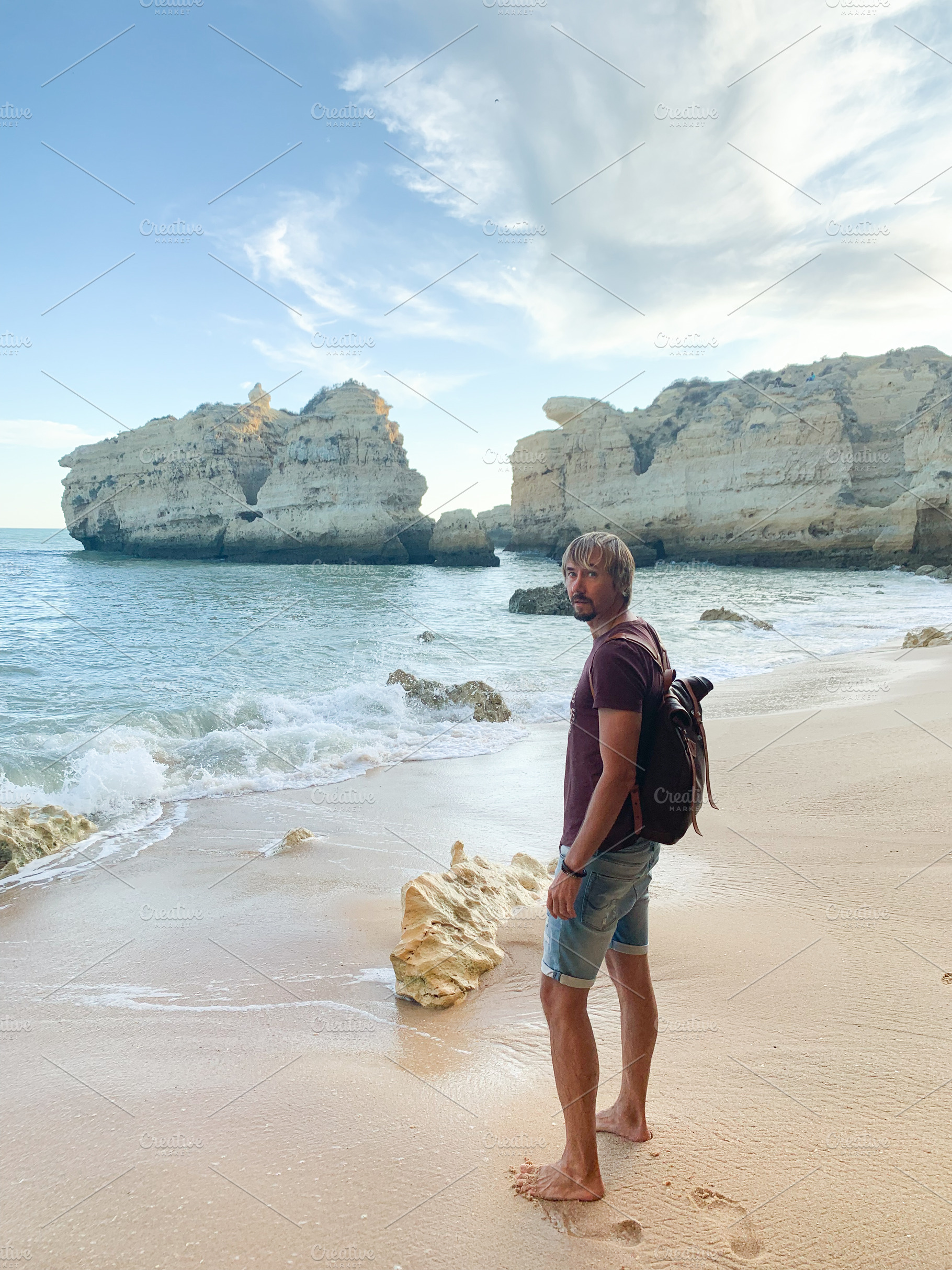 Man standing barefoot on sandy Algarve beach, a Holiday Photo by sebastianaraw