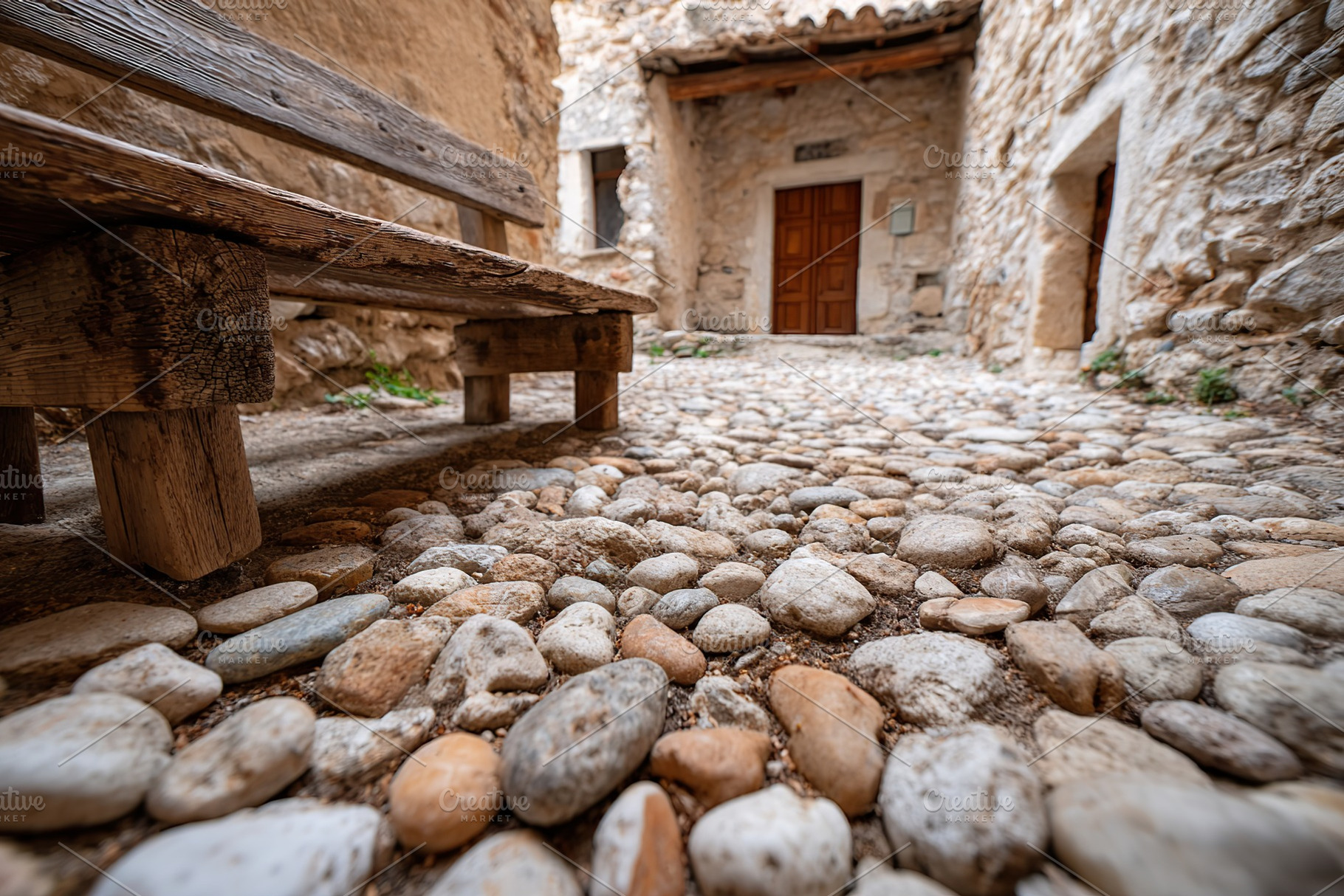 Cobblestone pathway and wooden bench in a rustic courtyard of an ancient buildi, a Photo by AlyaAnd