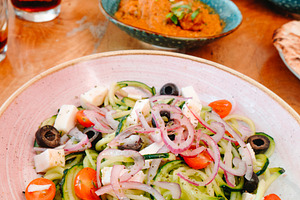 a bowl of spiralized cucumber salad on a table, a Photo by Nito