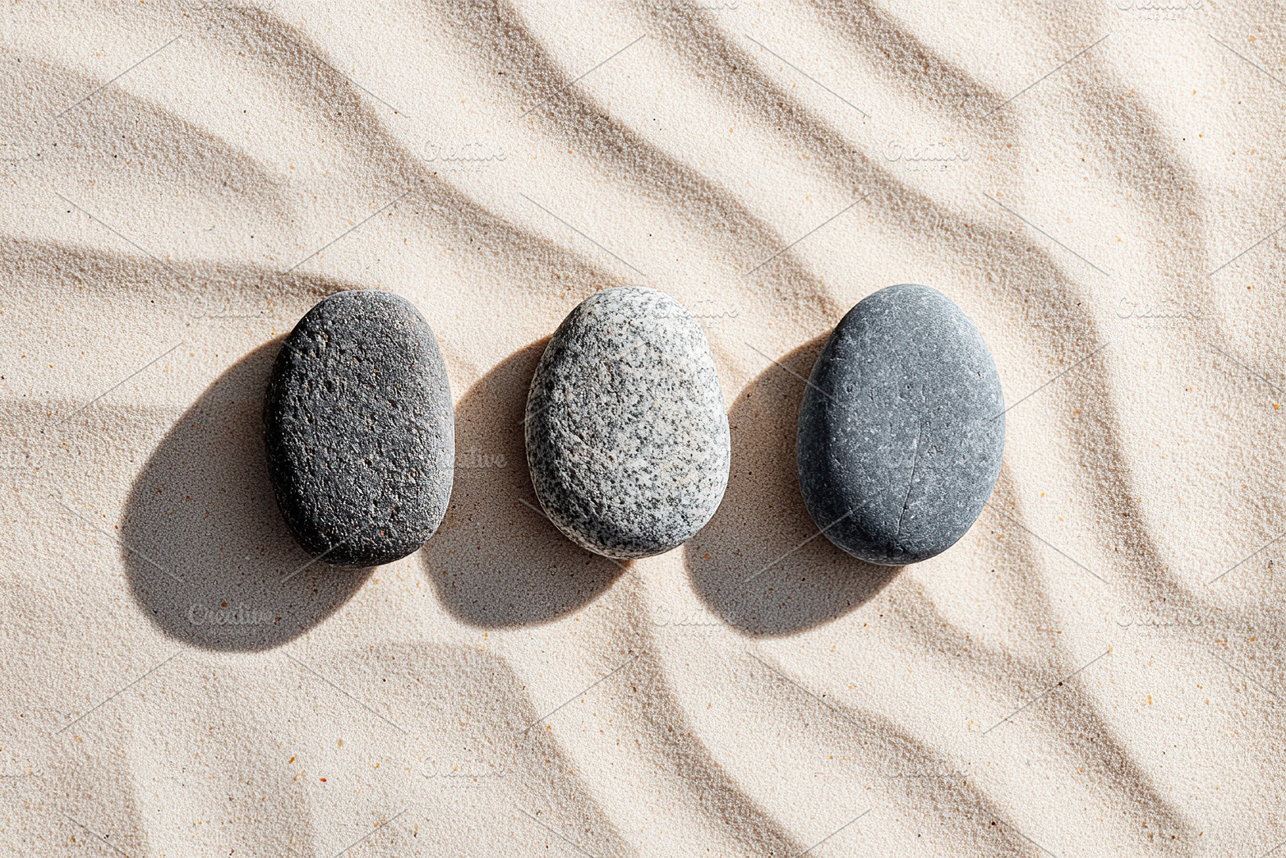 Textured stones on sandy surface create a harmonious natural arrangement in sun, a Background Photo by AlyaAnd