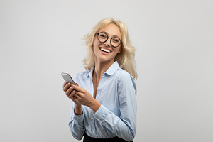 Excited businesswoman with smartphone smiling and looking at camera, female sec, a Photo by Prostock-Studio