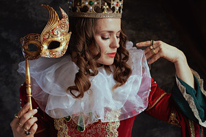 medieval queen in red dress with venetian mask, a Person Photo by Alliance Images