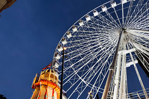 Manchester Ferris wheel at night beside illuminated tower and glowing city ligh, a Photo by AS photostudio
