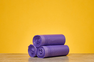 Three rolls of purple garbage bags stacked in a pyramid on a woo, a Background Photo by ndanko