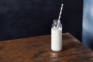 Glass bottle of milk with straw