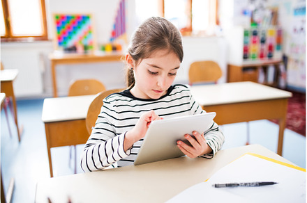 Portrait of cute schoolgirl sitting, a School & Education Photo by HalfPoint