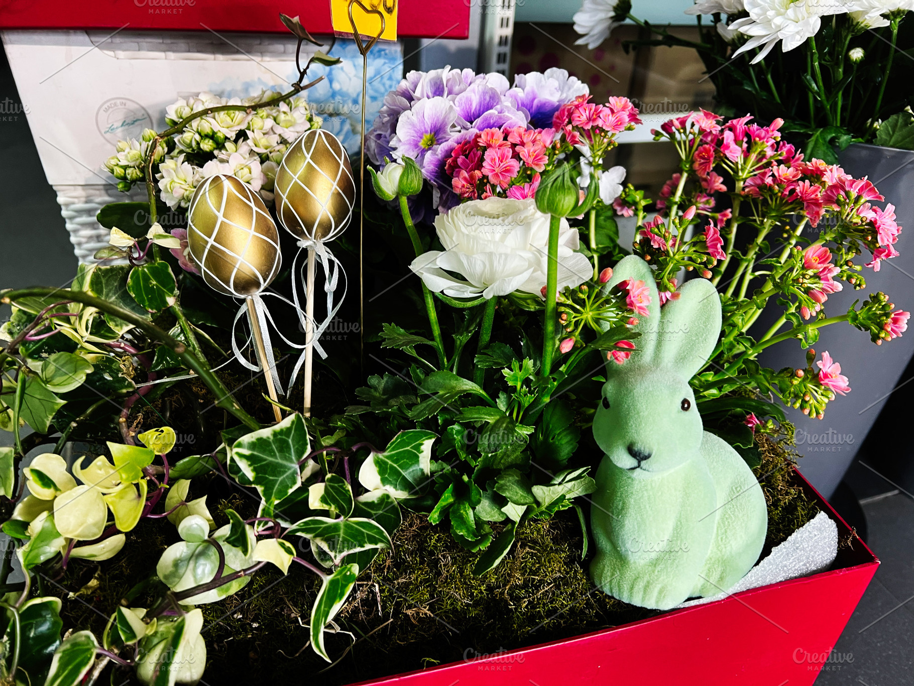 Decorative Easter arrangement with flowers, golden eggs, and a green bunny figu, a Photo by AS photostudio