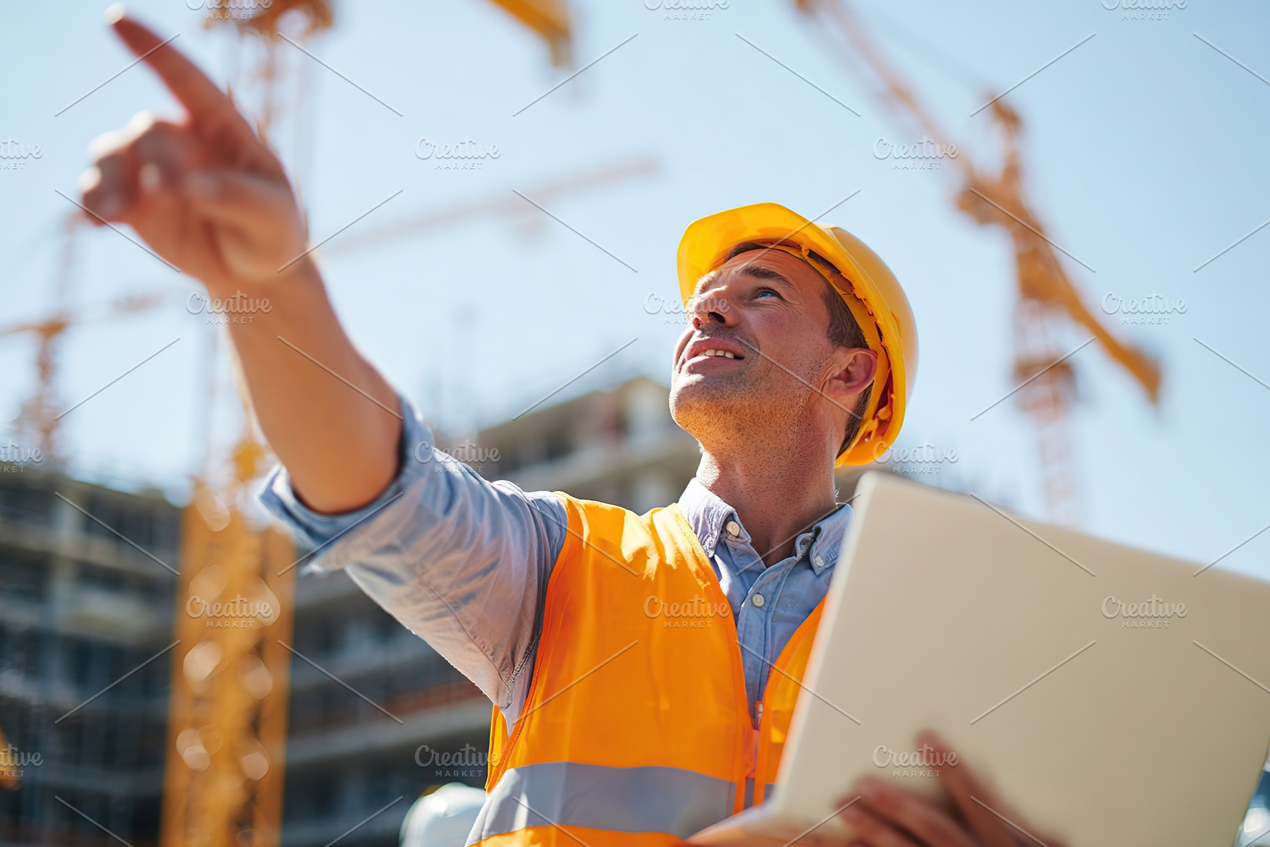 Young male architect points at construction site while overseeing project devel, a Photo by AlyaAnd