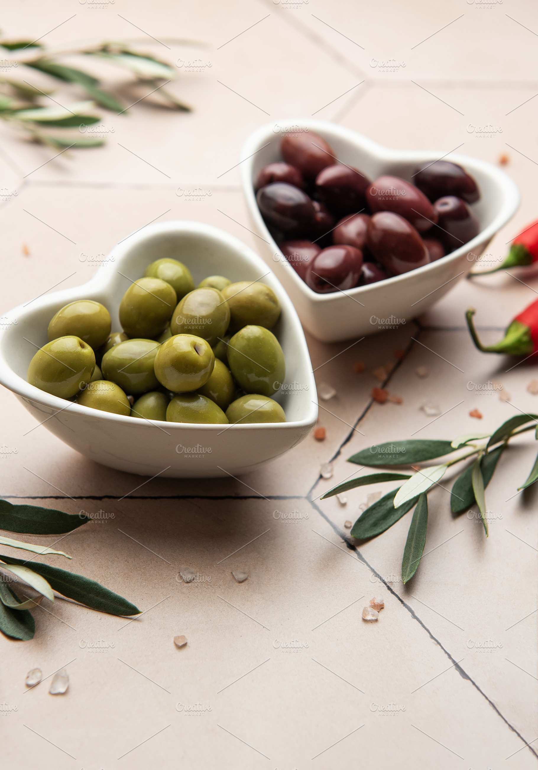 Heart shaped bowls containing green and black olives, olive bran, a Food & Drink Photo by Olena Rudo