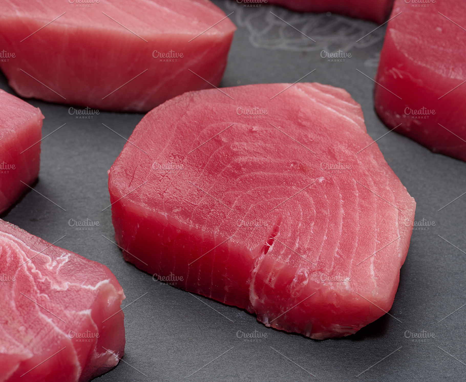 Raw tuna pieces on a black board, snack, a Food & Drink Photo by ndanko