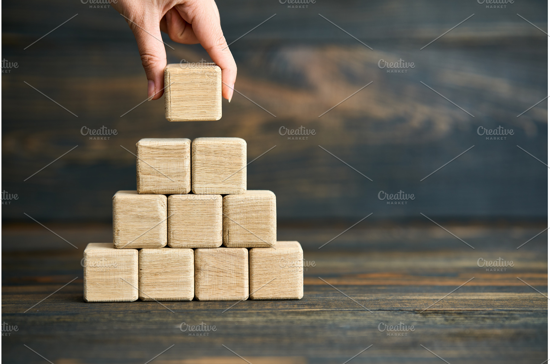 Hand placing last wooden cube on, a Business Photo by Gladkov photography