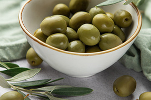 Fresh green olives with olive branches in a bowl, displaying med, a Food & Drink Photo by Olena Rudo