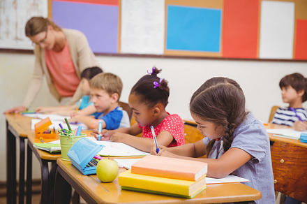 Cute pupils drawing at their desks, a Photo by wavebreak