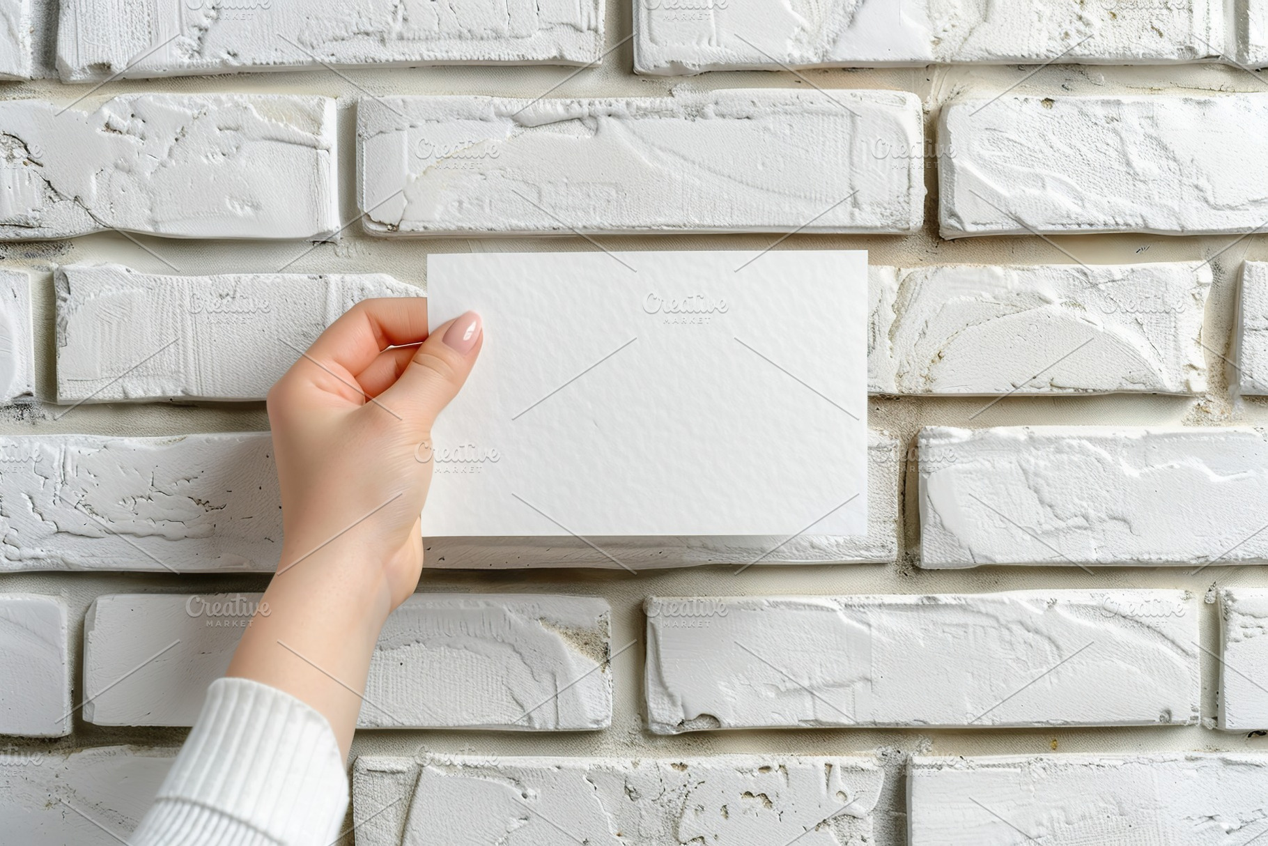 Female hand with blank paper card on white brick wall background, a Background Photo by AlyaAnd