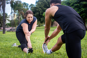 Man and woman stretching their legs together during outdoor workout