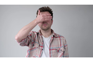 Young man covering his face by hand
