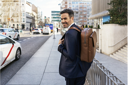 Businessman with backpack walking in, a Person Photo by nunezimage