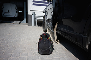 Toolbag beside a black car outdoors in a service area, a Transportation Photo by AS photostudio