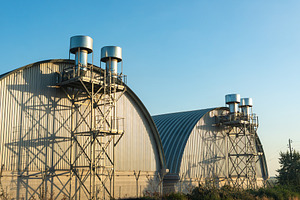 Modern industrial warehouses with metal vents and curved roofs, captured in sof, an Architecture Photo by Ales Munt