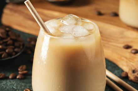 Ice coffee in a tall glass with cream poured over, ice cubes and beans on a dar, a Food & Drink Photo by Budarinphoto