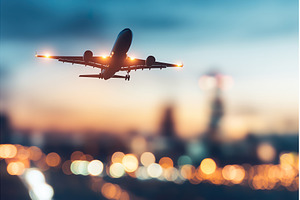 Airplane flying at dusk with city, a Transportation Photo by Lermont51