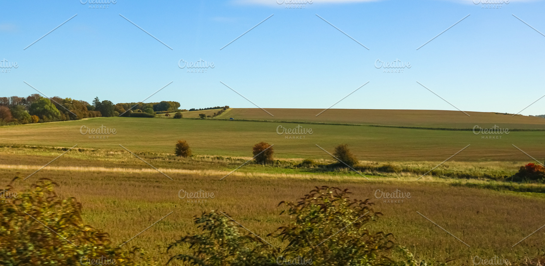 Rural landscape with rolling hills and agricultural fields under, a Photo by Studio ANNA
