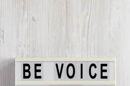 'Be voice not an echo' on a lightbox on a white wooden backgroun, a Business Photo by LiudmylaChuhunova