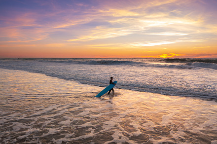 Surfer walking in ocean on sunset with surfboard, a Person Photo by andreonegin market