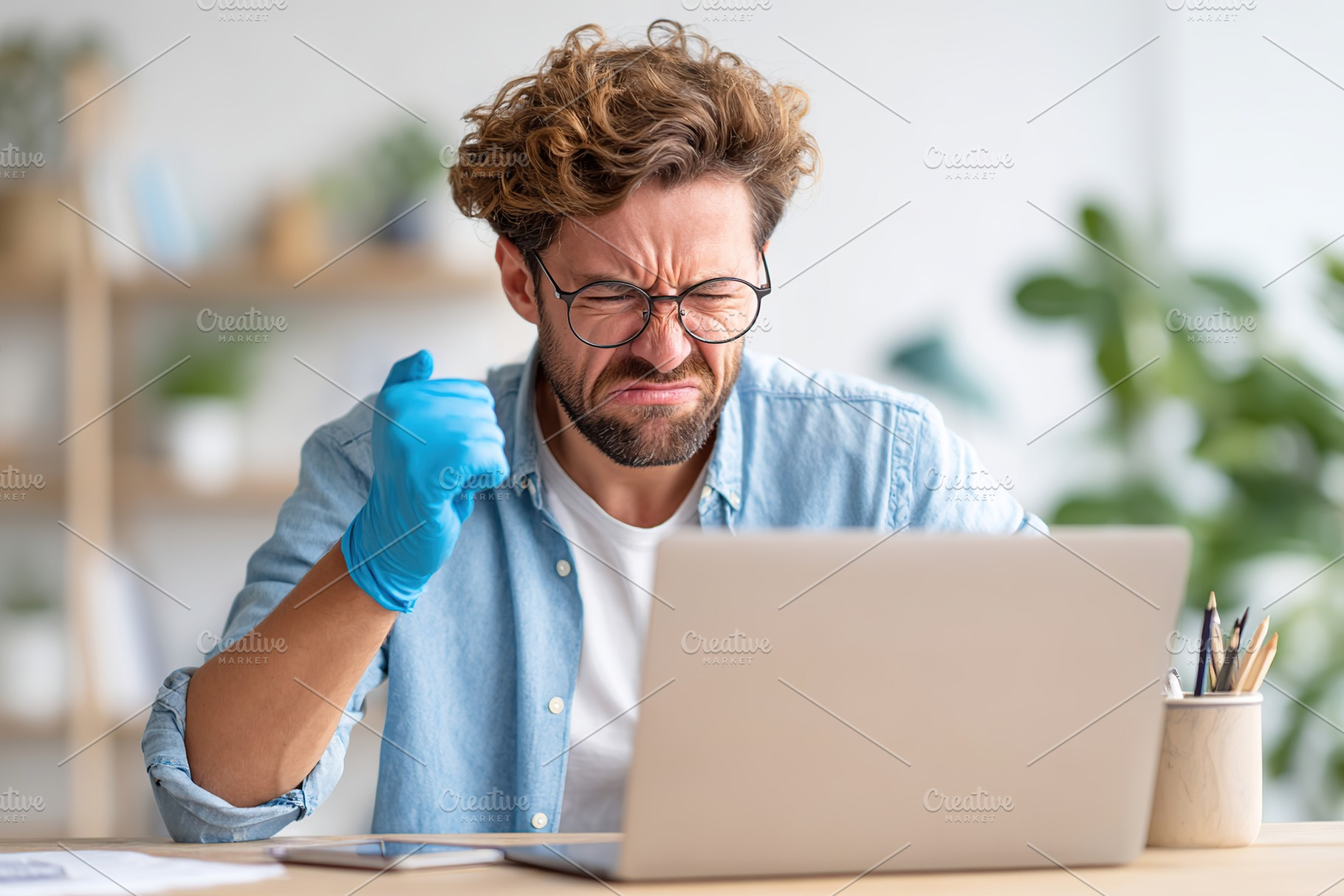 Man with curly hair and glasses reacts passionately while working on a laptop i, a Person Photo by AlyaAnd