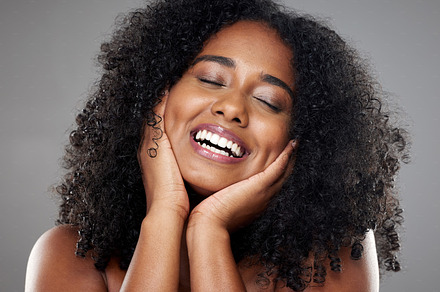 Black woman, skincare model with smile in studio portrait against grey wall background with happiness. Plus size beauty, happy cosmetic woman with glow skin for makeup cosmetics against dark backdrop, a Photo by Peopleimages.com