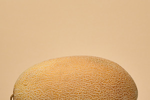Whole cantaloupe melon on white table, beige background, a Food & Drink Photo by ndanko