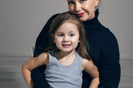 mother in a black sweater hugs her five-year-old daughter sitting on chair in t, a Person Photo by SaulichPhoto