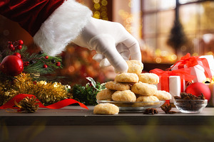 Santa's hand taking cookie on table with Christmas decorations, a Food & Drink Photo by Davizro's Market