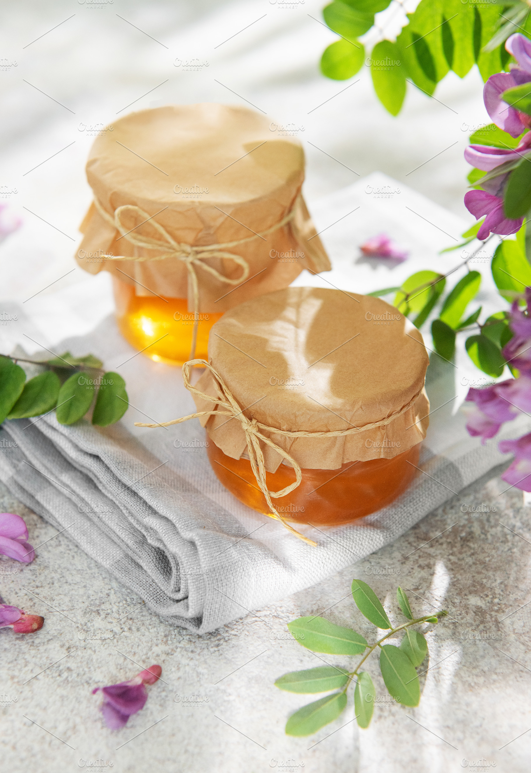 Honey jars with acacia flowers on white surface, a Food & Drink Photo by Olena Rudo