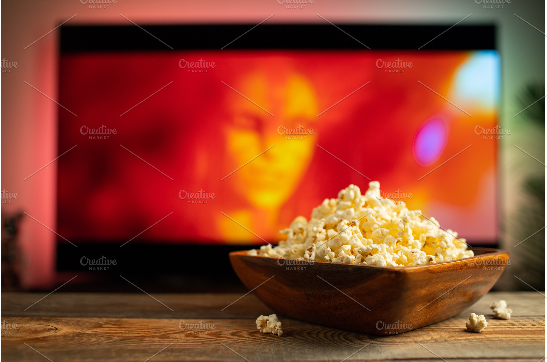 A wooden bowl of popcorn and remote, a Technology Photo by Budarinphoto