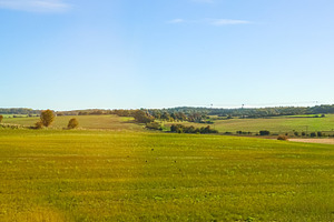 Green vast rural landscape with fields and clear blue sky showin, a Photo by Studio ANNA