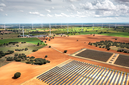 Solar panel farm and wind turbines in countryside during daytime
