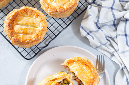 Sliced beef pot pie on plate and pies on cooling rack, vertical, top view, a Food & Drink Photo by iuliia_n