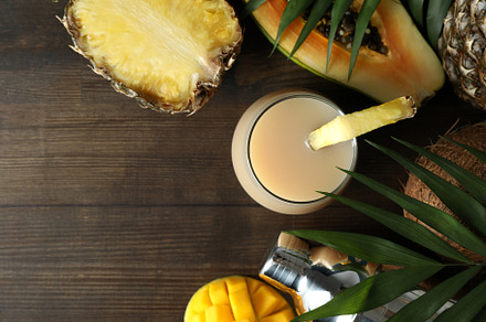 Pina colada cocktail and ingredients on wooden table, a Food & Drink Photo by AtlasStudio