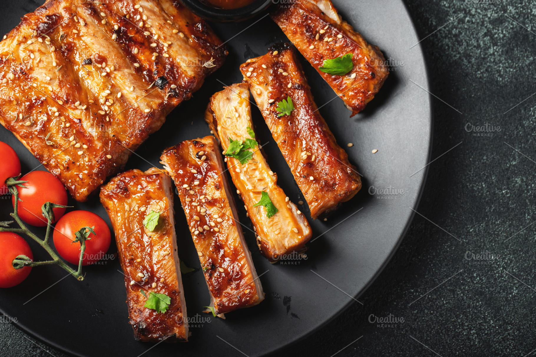 Hot grilled spare ribs from a summer BBQ served on a plate with sauce. Top view, a Food & Drink Photo by Budarinphoto