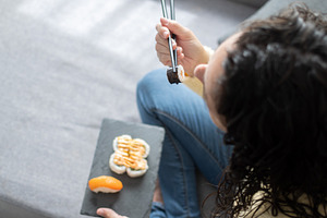 Woman Enjoying Sushi While Relaxing on Sofa at Home, a Person Photo by etorres69
