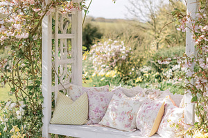 Pergola covered with cherry blossom and white garden bench with, a Photo by Studio ANNA