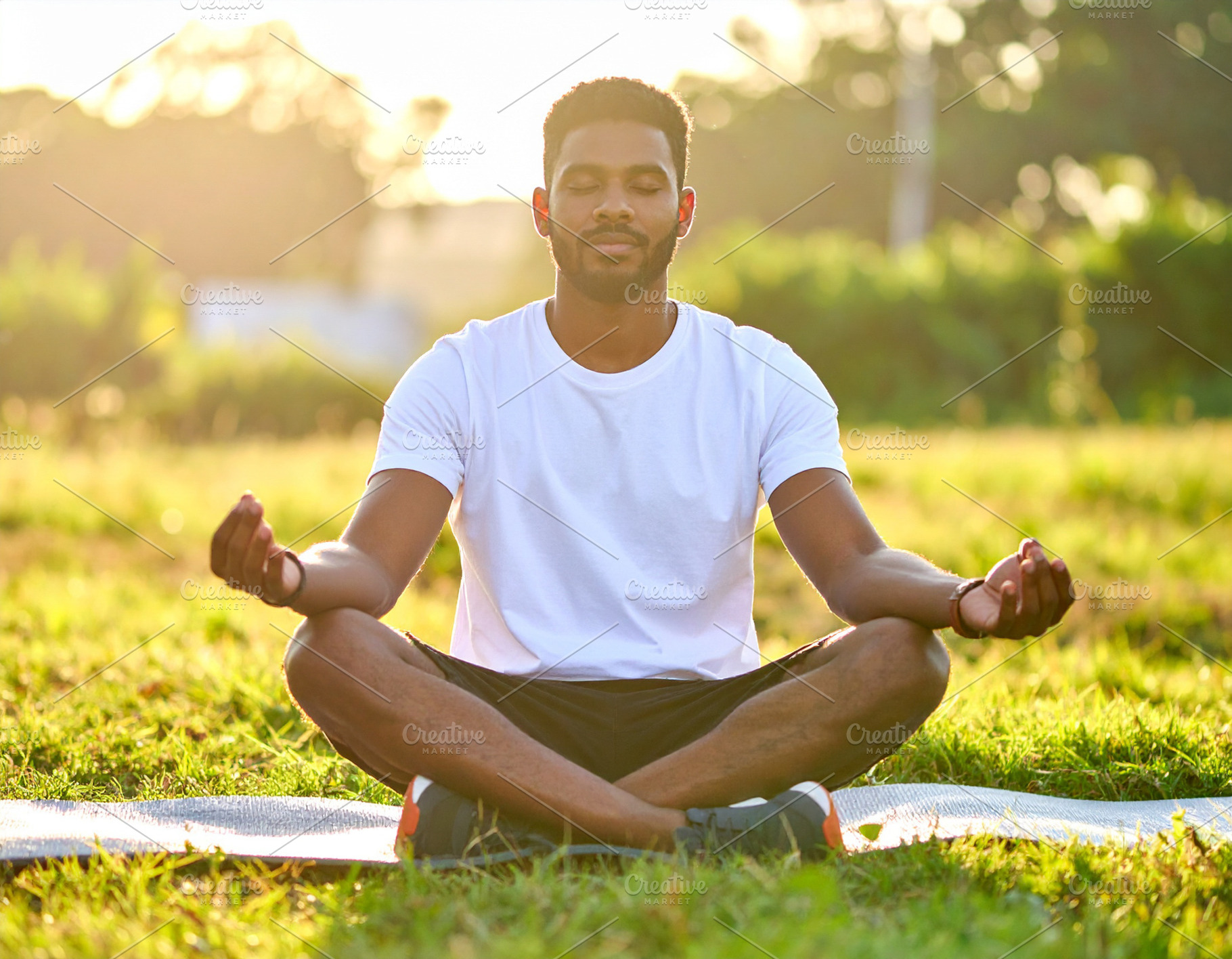 Diverse man meditating outdoors at sunrise, a Health & Medical Photo by DanFLCreativo