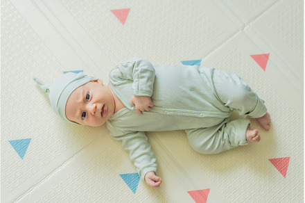 Adorable baby in a green hat lying, a Person Photo by Elizaveta Galitskaya
