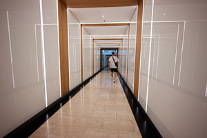 Modern corridor with seamless lighting and lone traveler walking into a bright, a Photo by AS photostudio
