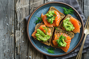 Toast bread with salted salmon and guacamole avocado on wooden table, a Food & Drink Photo by AlyaAnd