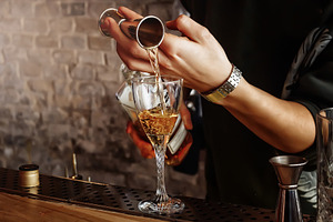 The barman is preparing a cocktail containing cocktail, bar, and drink