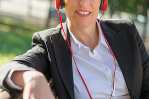 Smiling businesswoman with red headphones outdoors, a Photo by RF Images